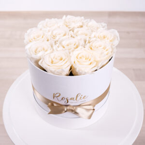 scatola con 12 rose bianche panna e nastro dorato su tavolino bianco