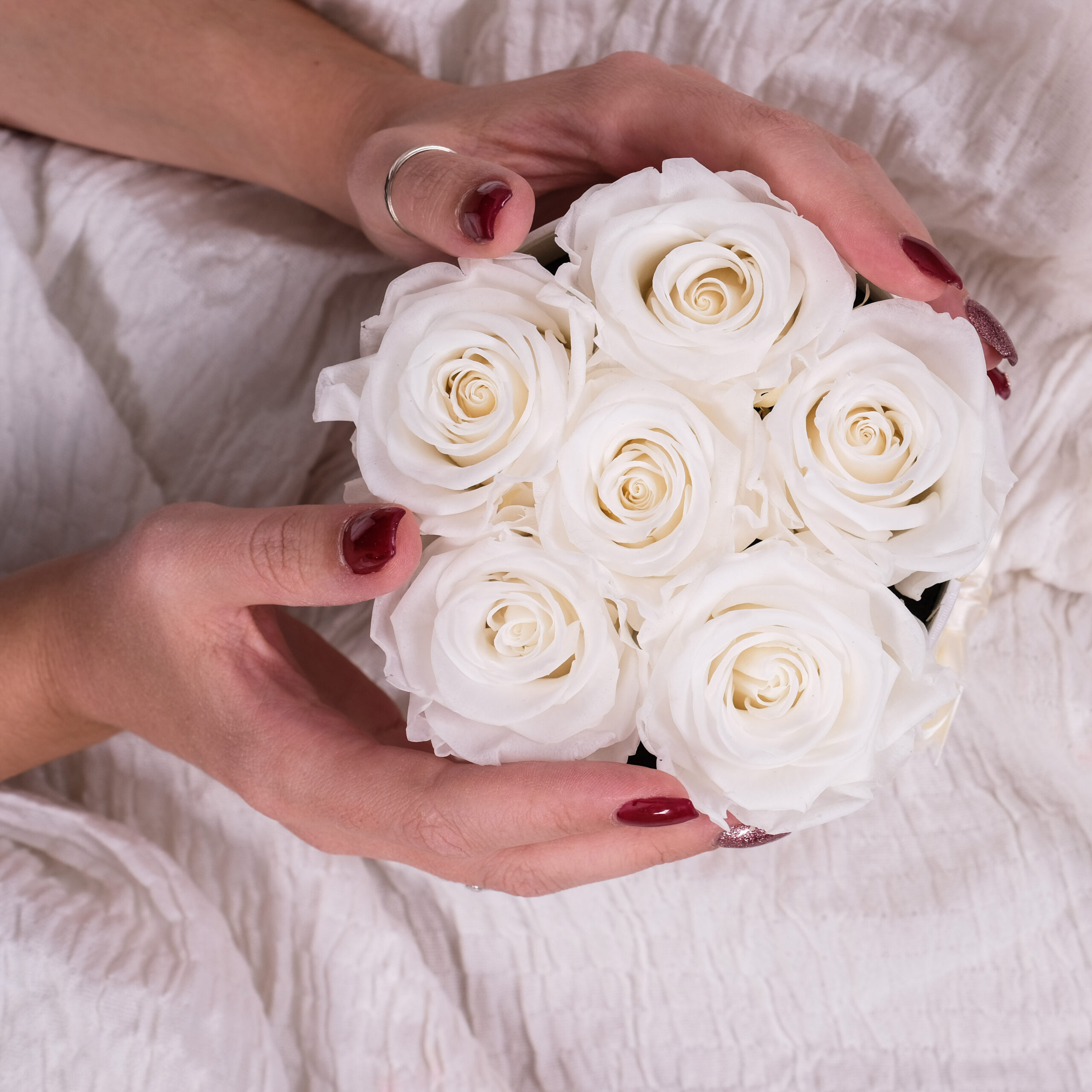 rose stabilizzate bianche in scatola tonda con mani femminili
