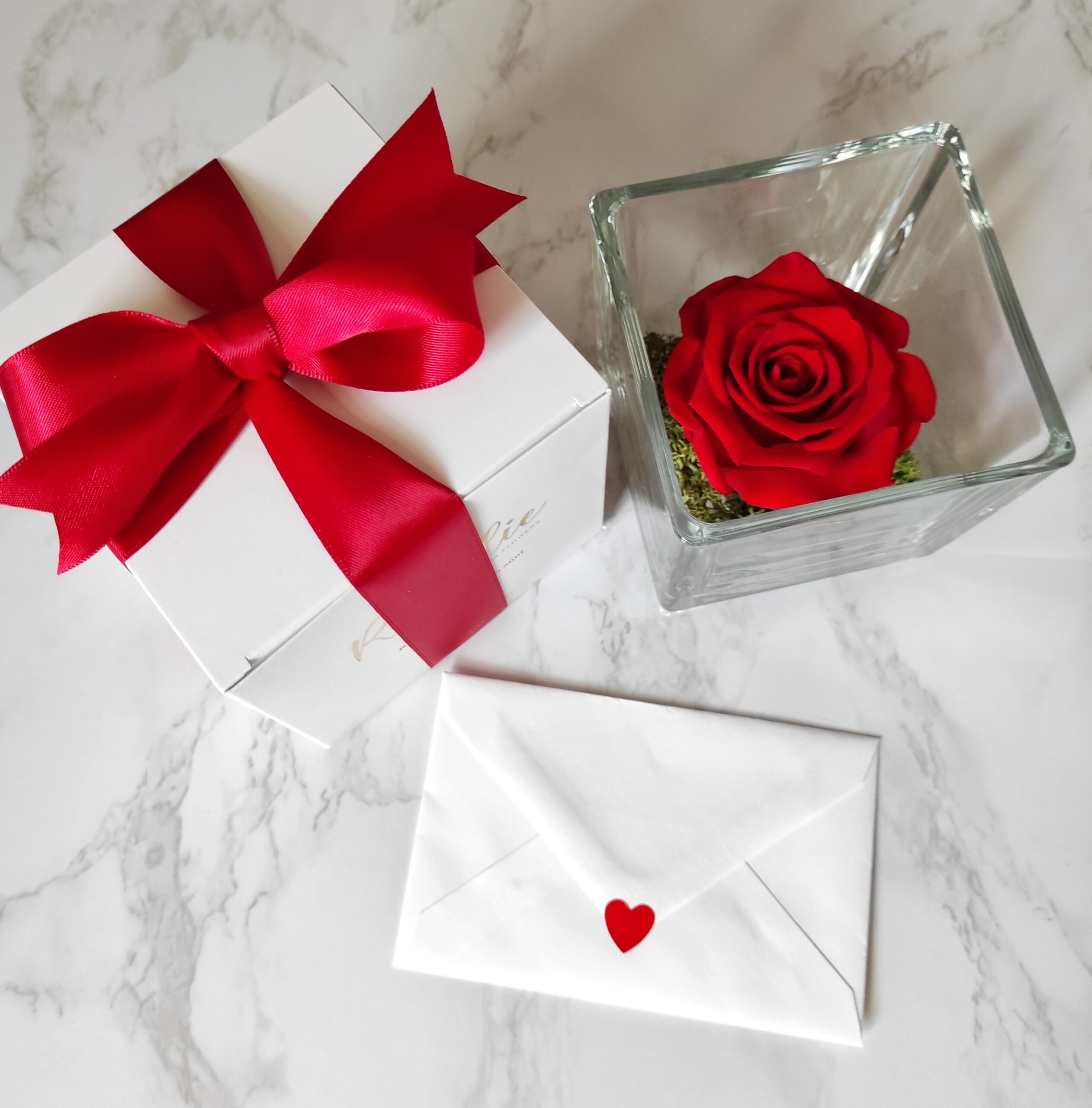 rosa rossa stabilizzata in cubo di vetro con confezione regalo con nastro rosso e biglietto