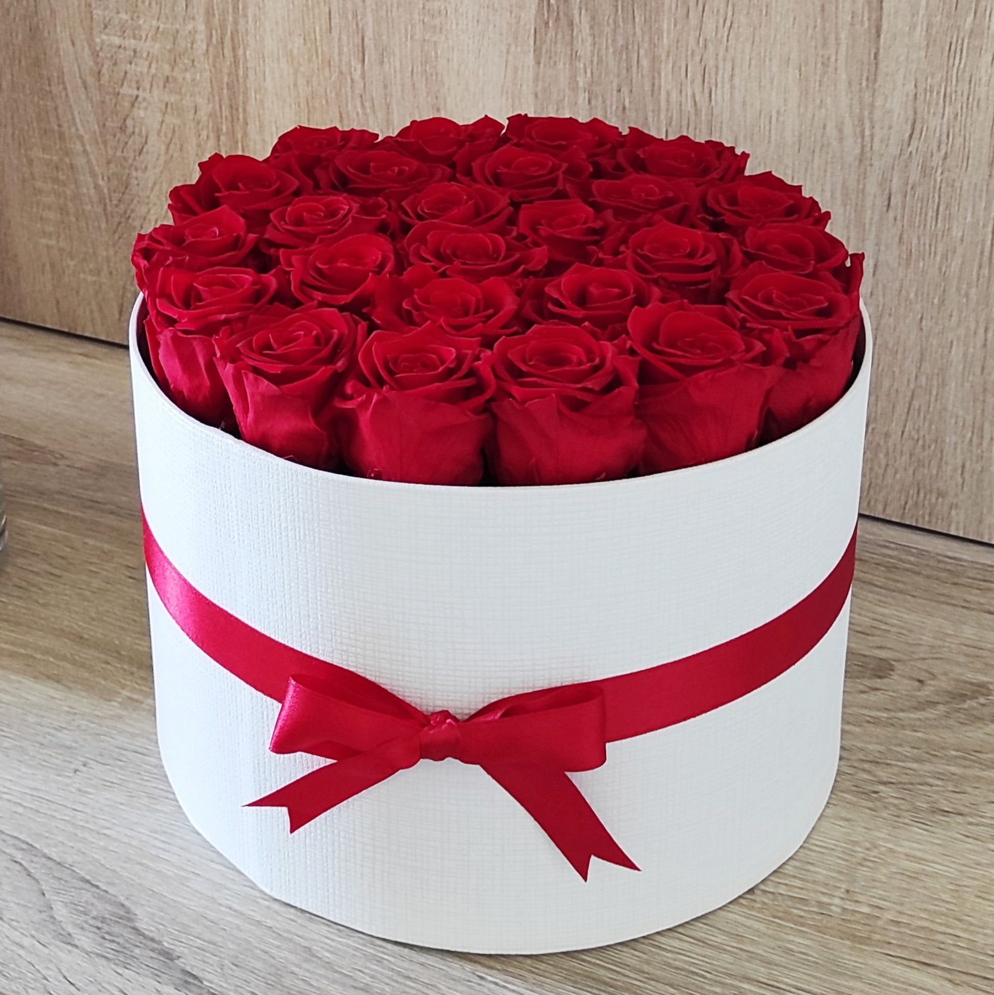 scatola tonda bianca con 25 rose stabilizzate di colore rosso e nastro rosso abbinato